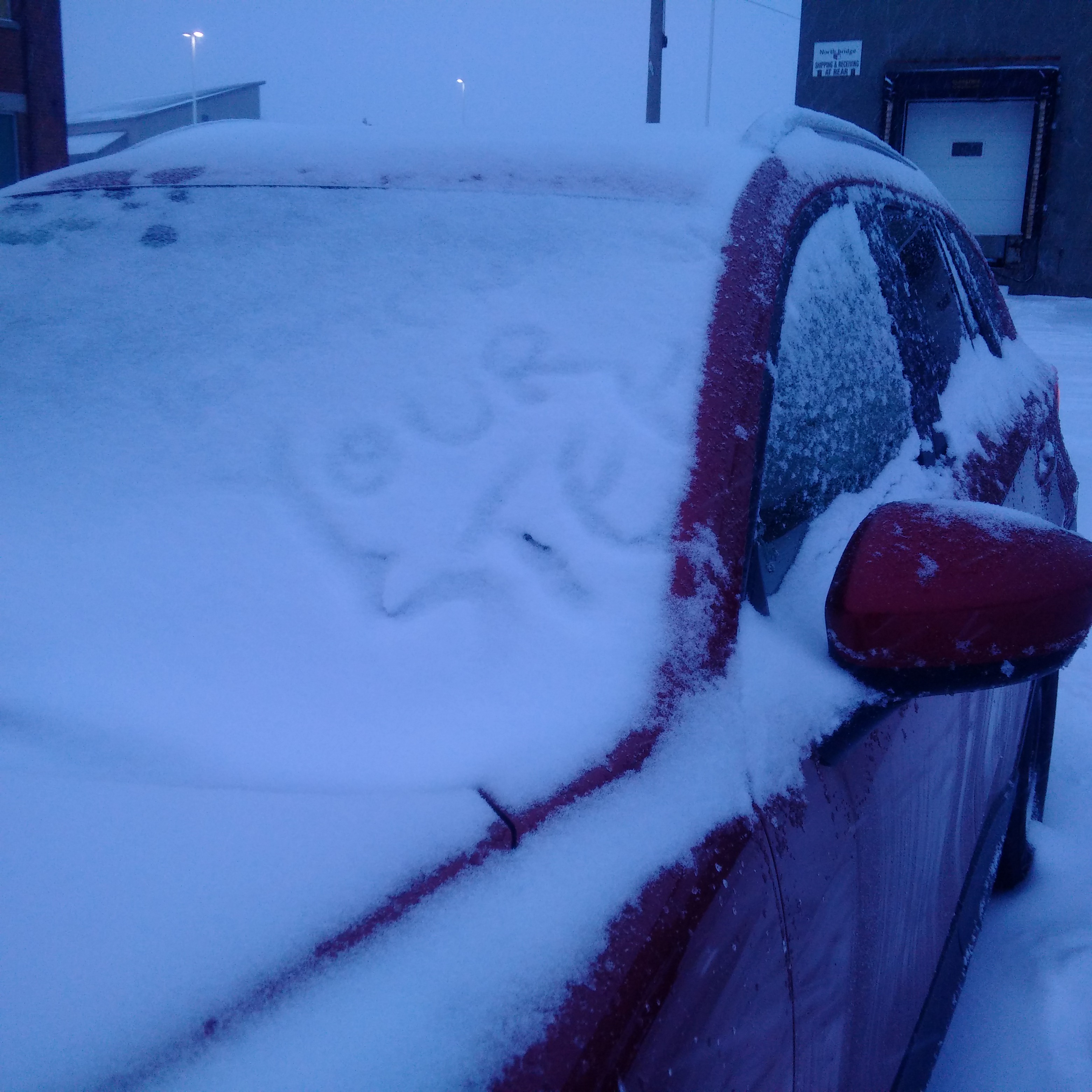 A red vehicle with snow on its windshield